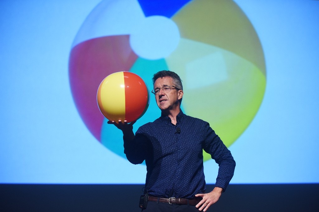 Paul McGee balancing a beachball on stage during a SUMO education session